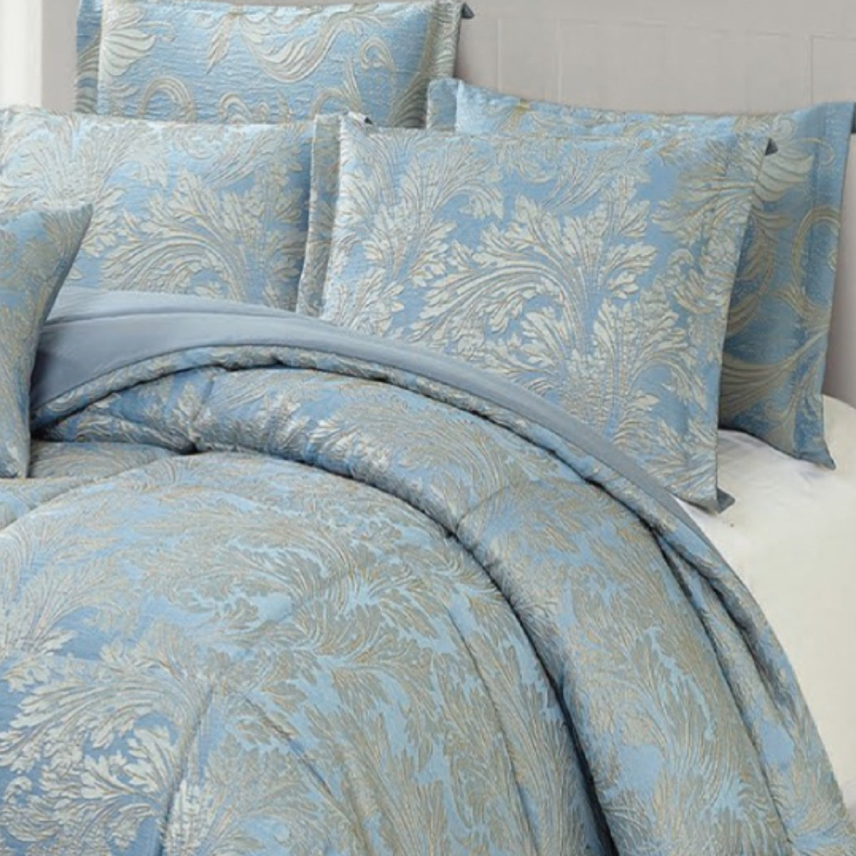 Full view of luxury blue and silver damask jacquard comforter with matching pillows in a bright bedroom
