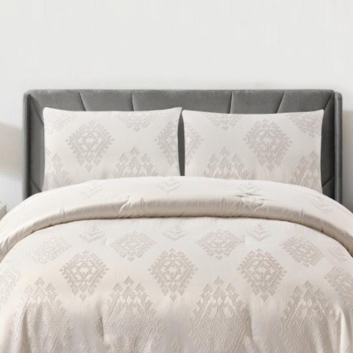 Full view of off-white geometric jacquard comforter and matching pillow shams in a bright bedroom