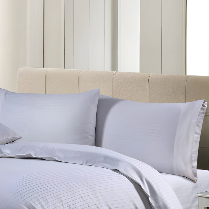 Soft white cotton bedding with delicate pinstripe patterns and matching pillows.
