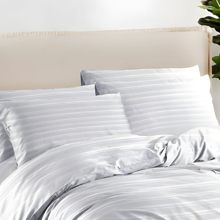 Soft white bedding with subtle stripe patterns and matching pillowcases.