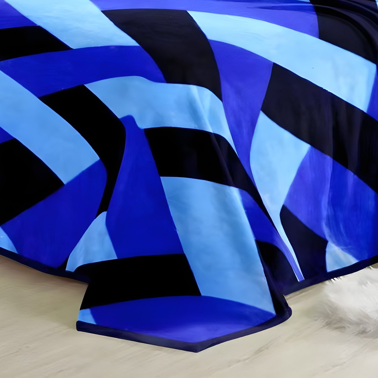Close-up of fluffy blue and black geometric plush blanket fabric showing soft folds and borders.