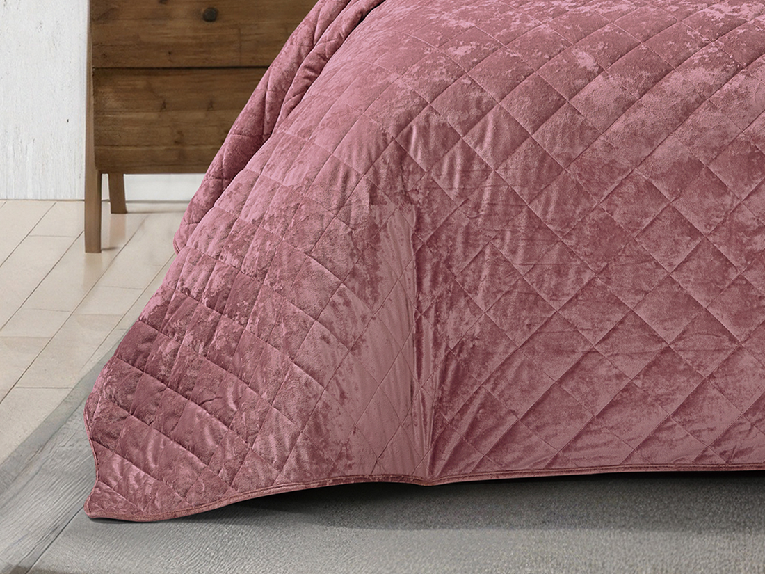 Soft blush pink velvet bed cover with matching pillows in a sophisticated bedroom.