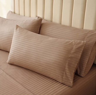 Full bedroom view displaying a brown striped sheet set with layered pillowcases on a modern bed.