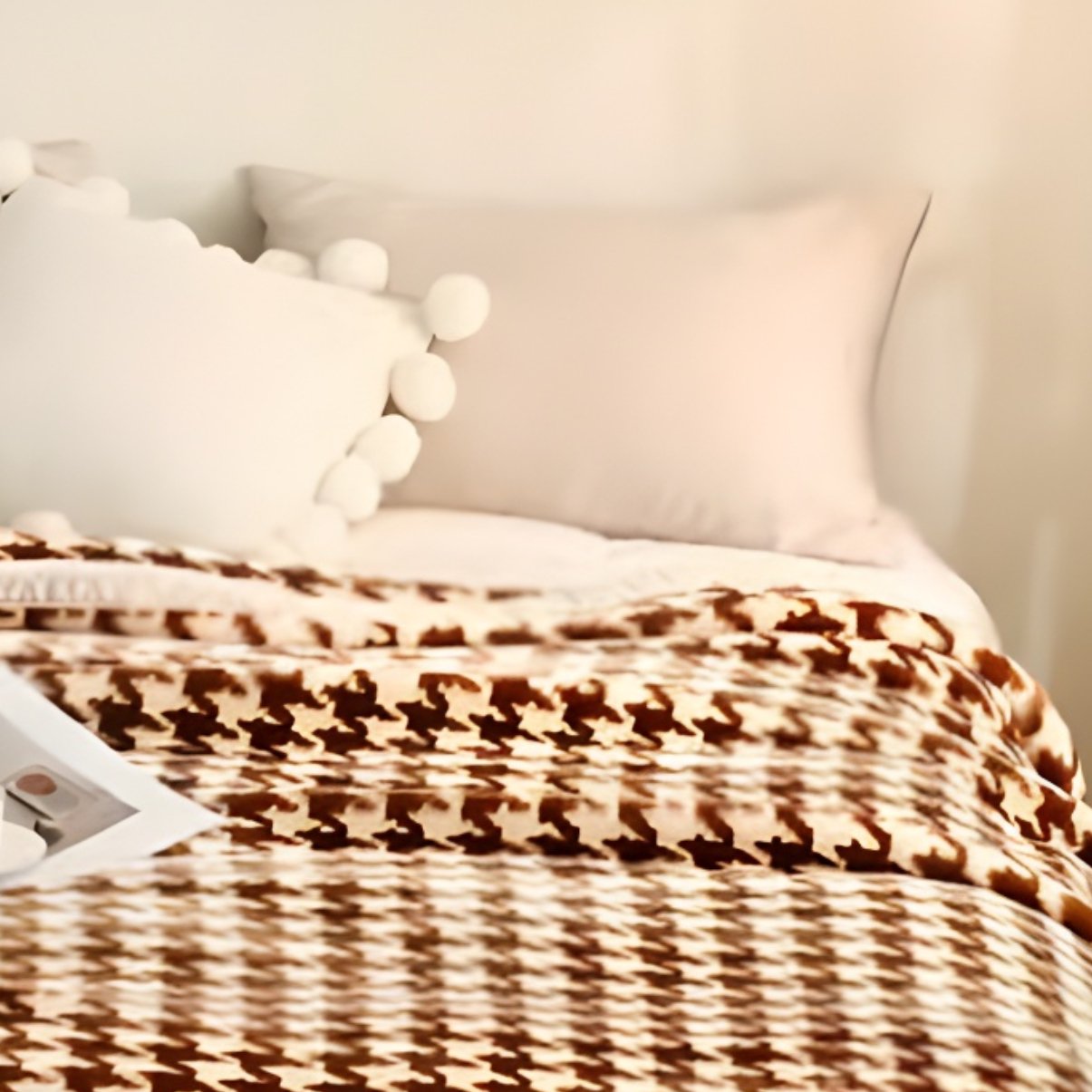 Full view of a brown and beige houndstooth patterned plush blanket on a mattress in a cozy bedroom setting