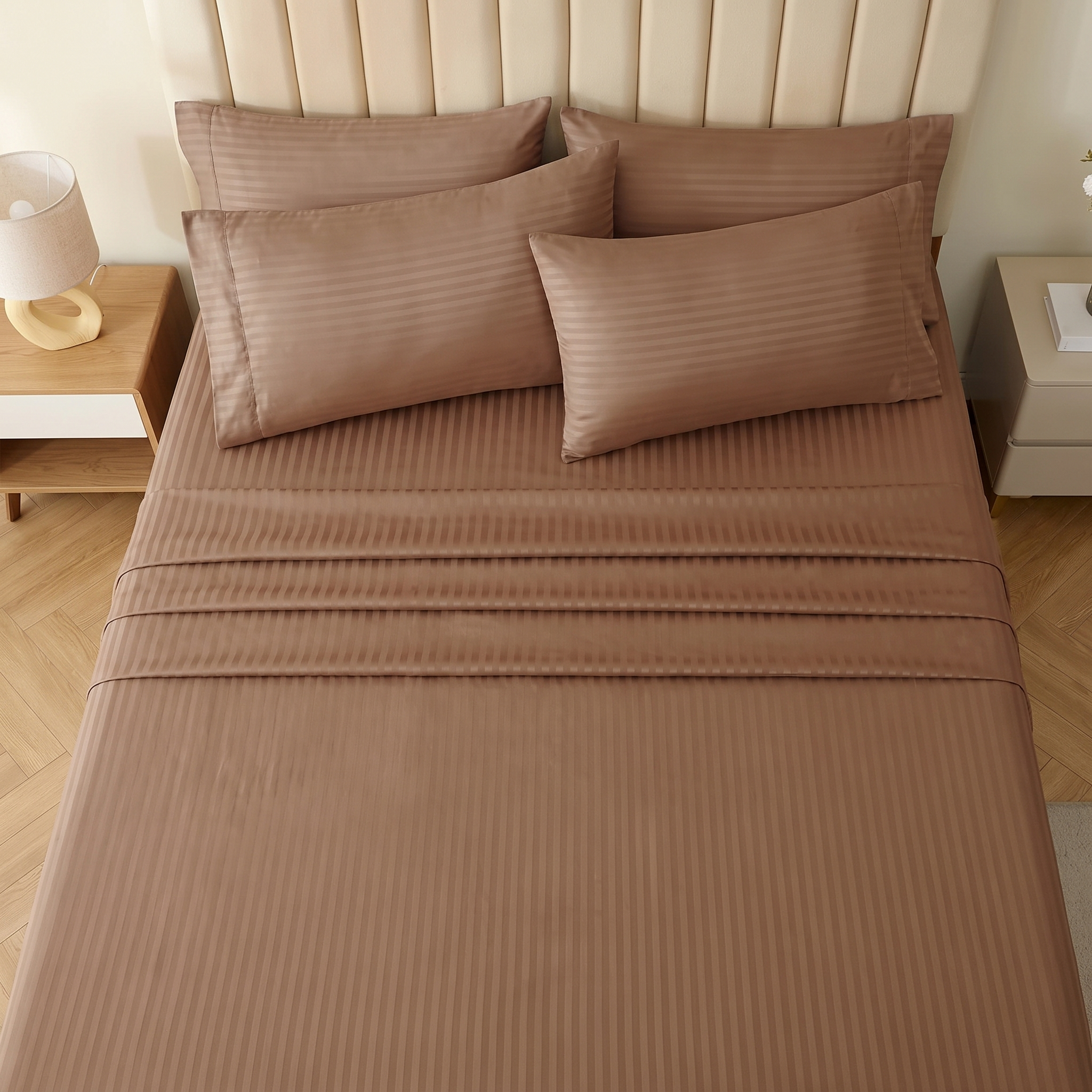 Brown damask stripe bed sheets and pillowcases arranged on a contemporary upholstered bed frame