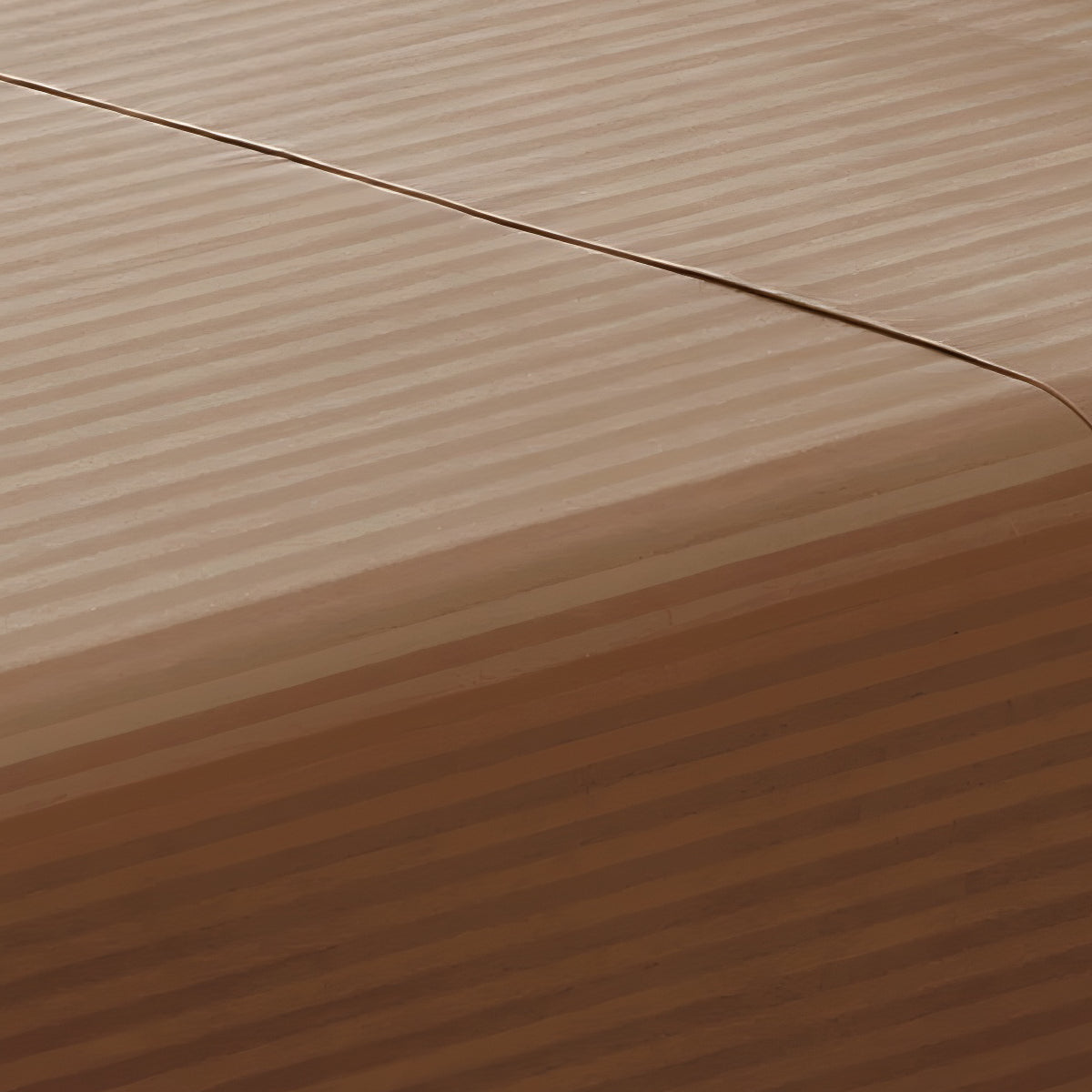 Close-up perspective of the smooth satin stripe texture of a brown cotton rich fitted sheet