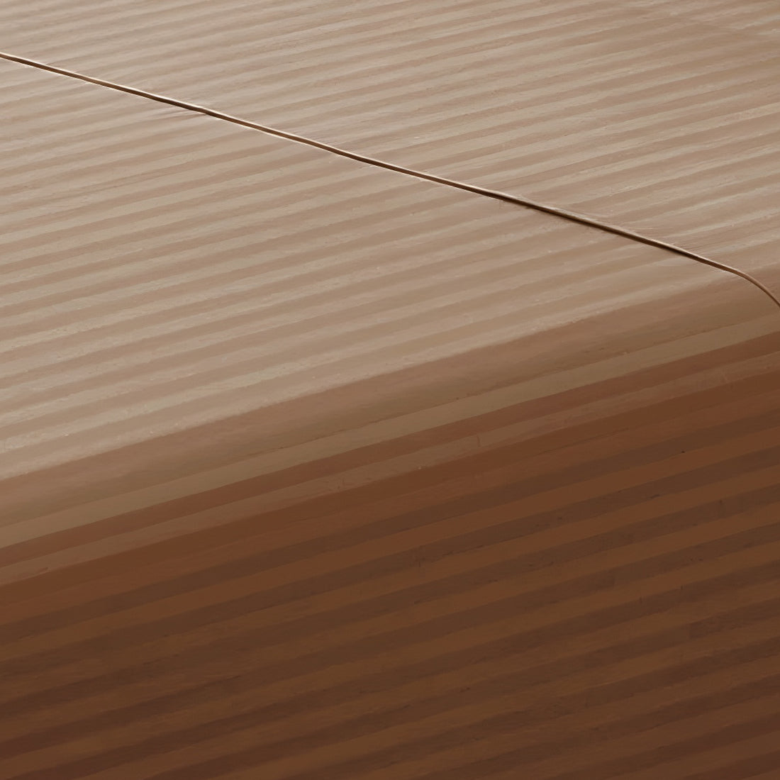 Close-up perspective of the smooth satin stripe texture of a brown cotton rich fitted sheet