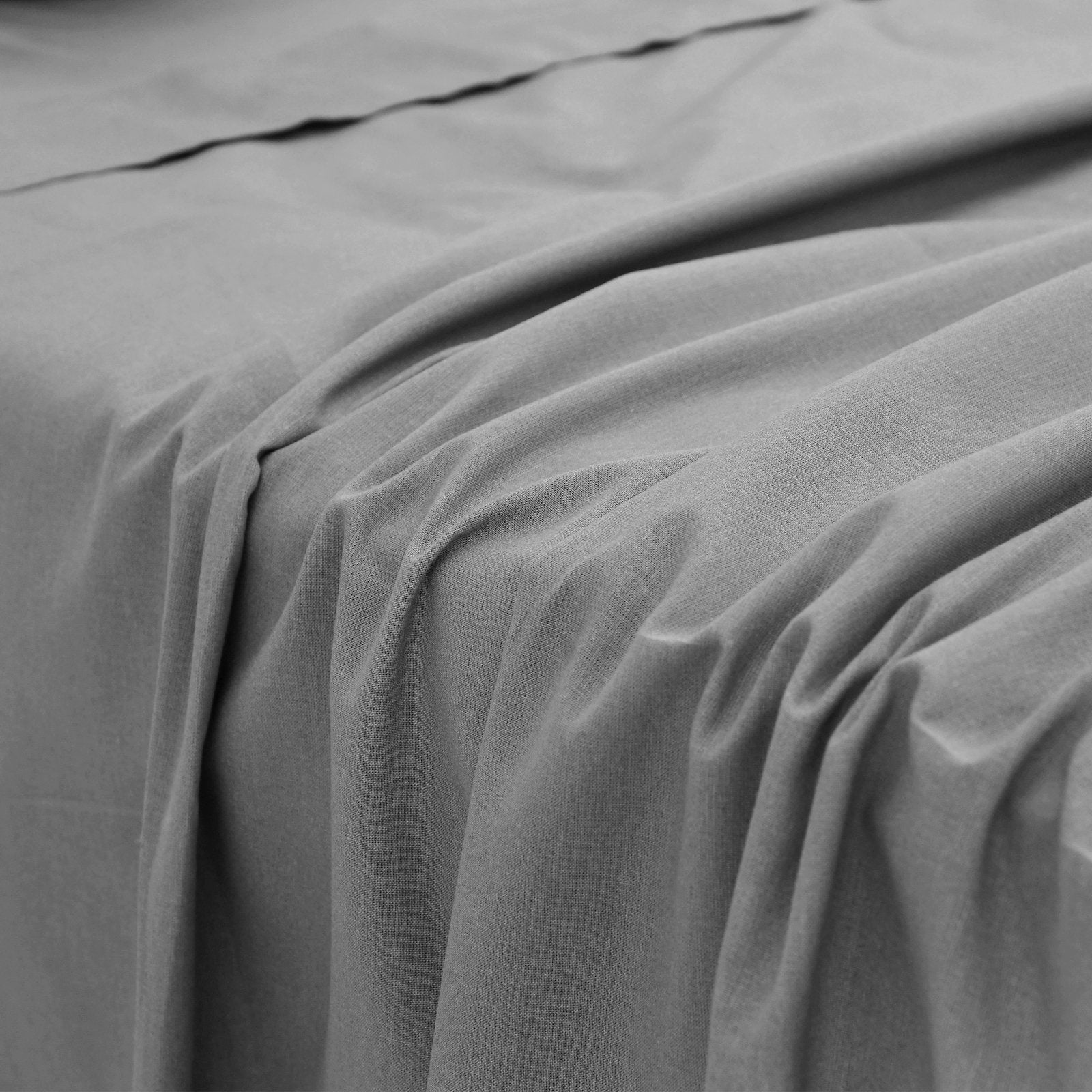 Close-up perspective of the smooth, soft fabric folds and texture of a charcoal grey bamboo bed sheet