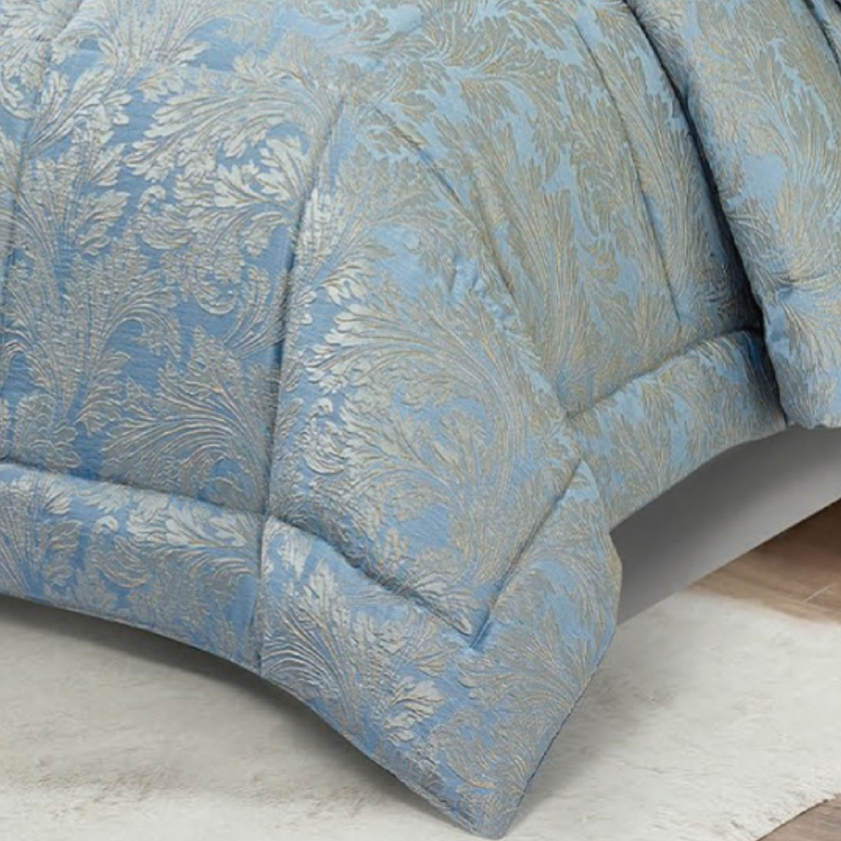 Close-up of textured blue jacquard fabric showing the ornate damask weave and quilted border.