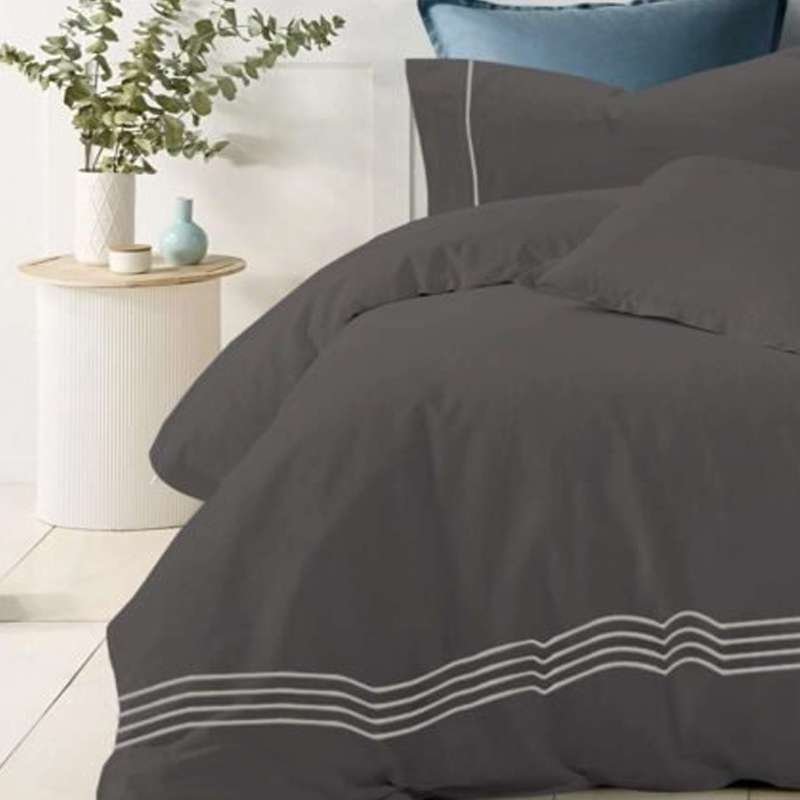 Charcoal quilt cover styled with blue cushions in a contemporary bedroom.