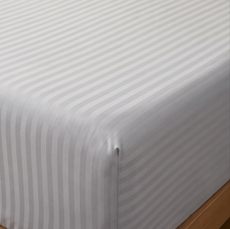 Side perspective of stacked silver gray cotton rich pillowcases arranged neatly on a bed