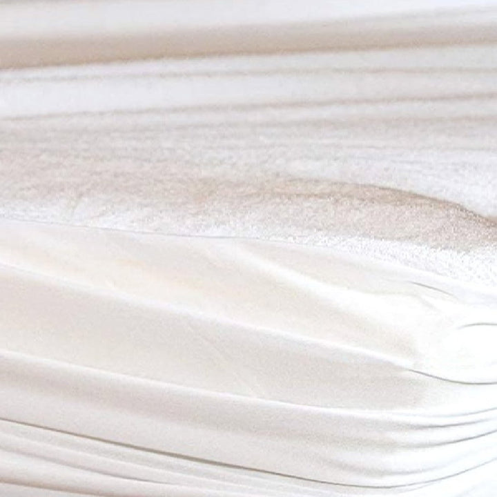 Side view of an elasticated white waterproof terry cloth mattress protector fitted snugly over a mattress corner