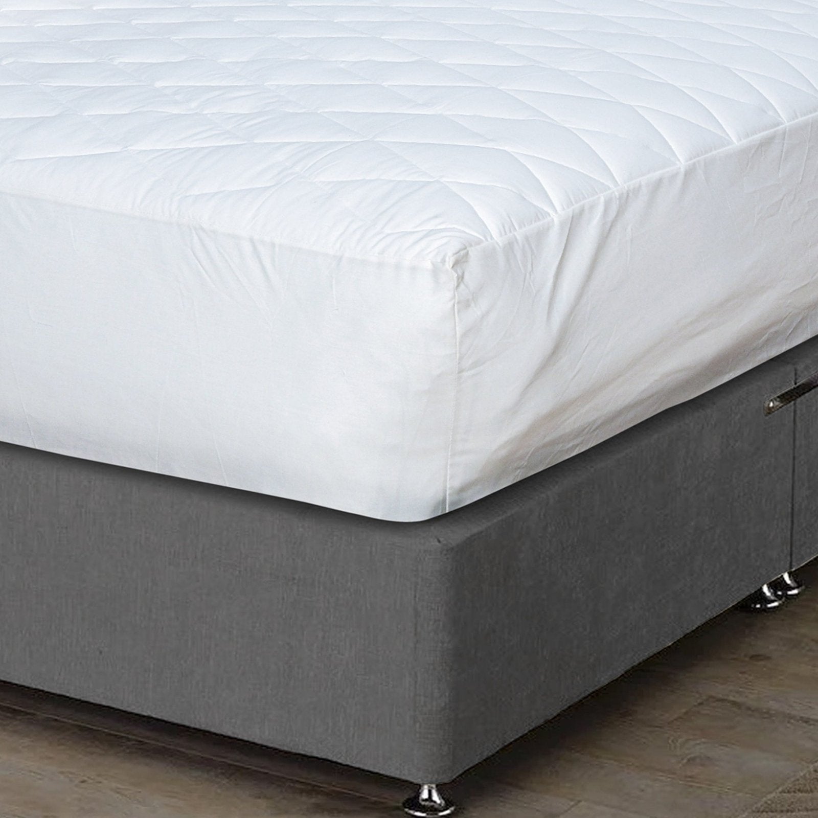 Close-up perspective of the diamond quilted pattern on a white bed protector and pillowcases