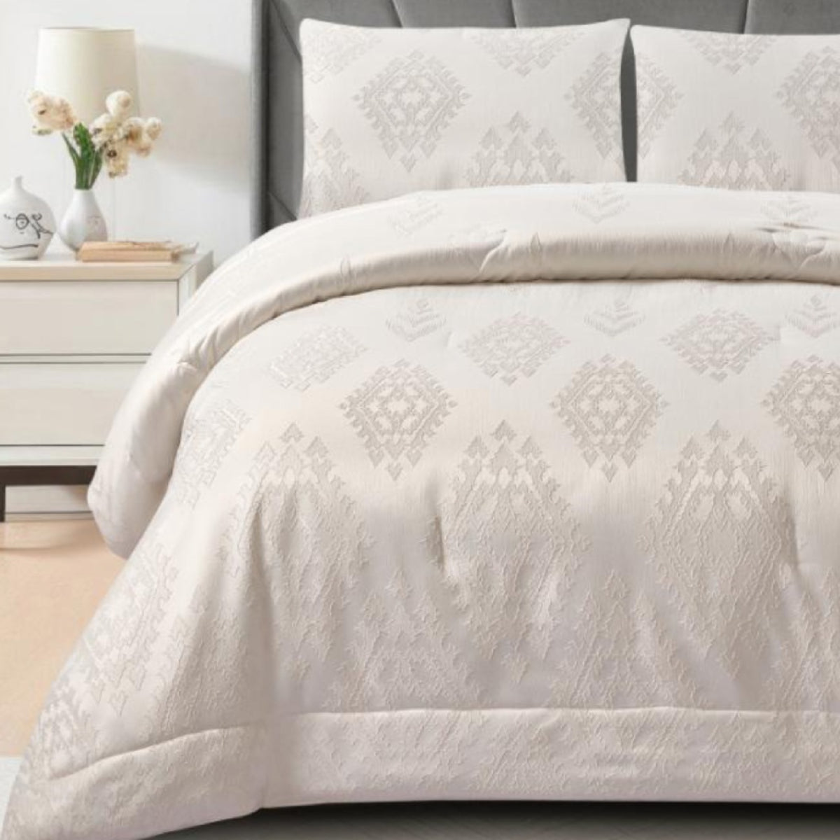 Close-up of white textured jacquard fabric highlighting the woven diamond motifs and quilted border