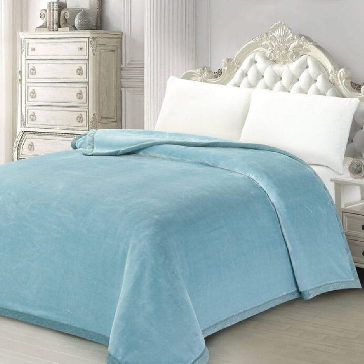 Super soft 3kg glacier mist blue mink blanket with folded hem draped over an ornate white tufted bed