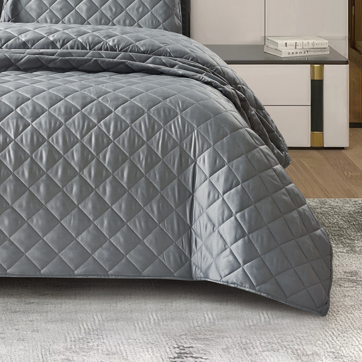 Soft grey quilted bed cover with matching pillows in a contemporary bedroom.