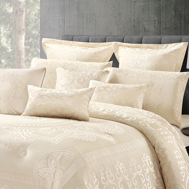 Elegant cream jacquard comforter set with ornate designs and coordinating pillowcases in a modern bedroom.