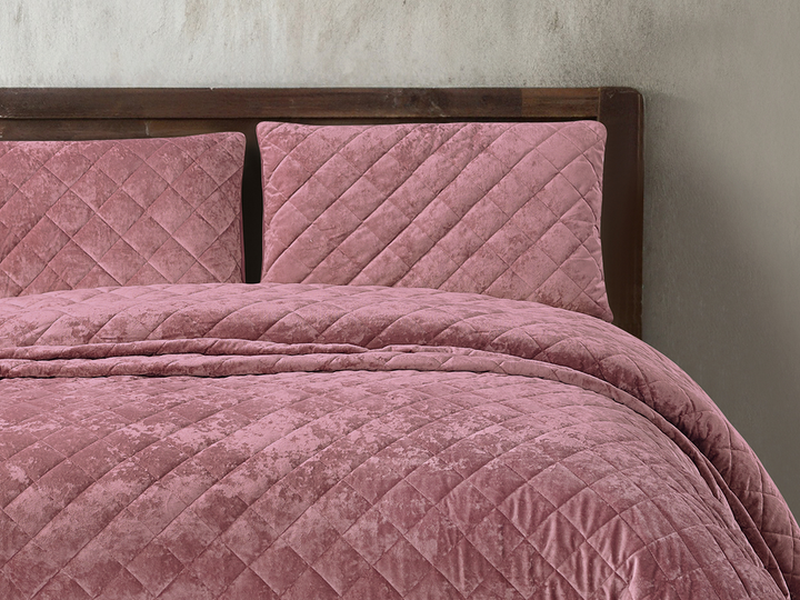 Luxury dusty pink velvet bedspread featuring a diamond quilted pattern.