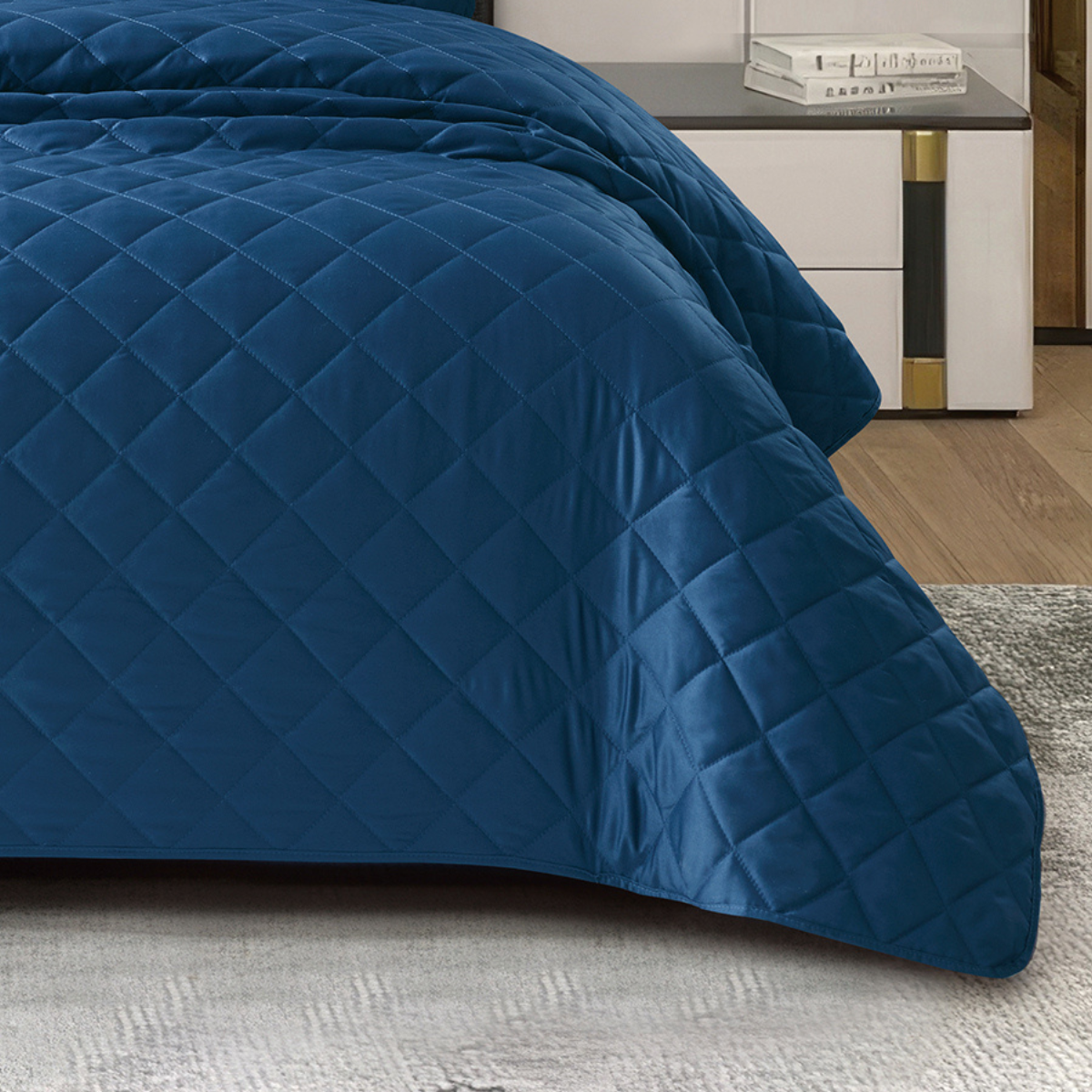 Close-up of a navy blue silk bedspread showcasing its diamond quilted texture and soft fabric.