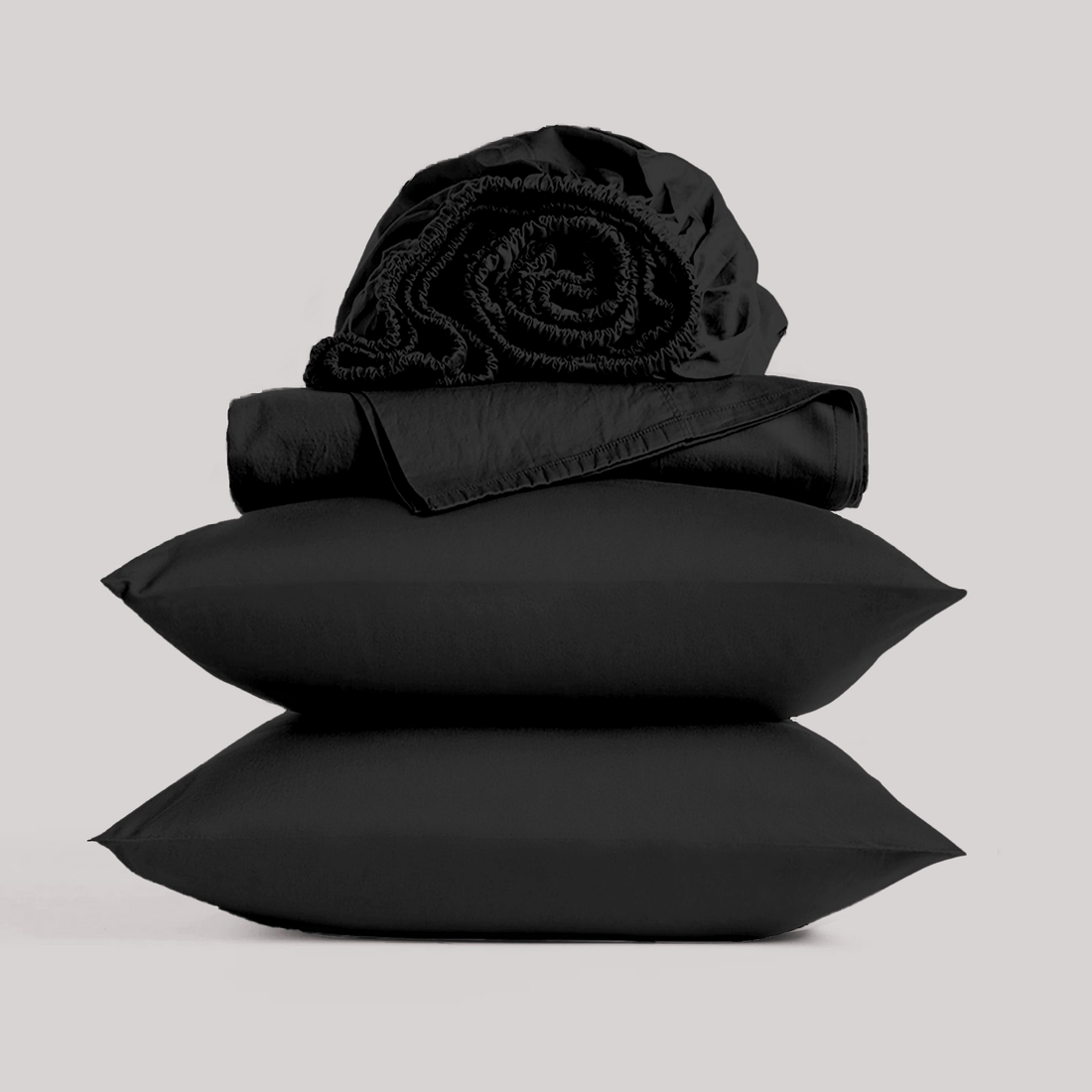 Neatly folded and rolled black bamboo sheet set isolated on a plain studio background.
