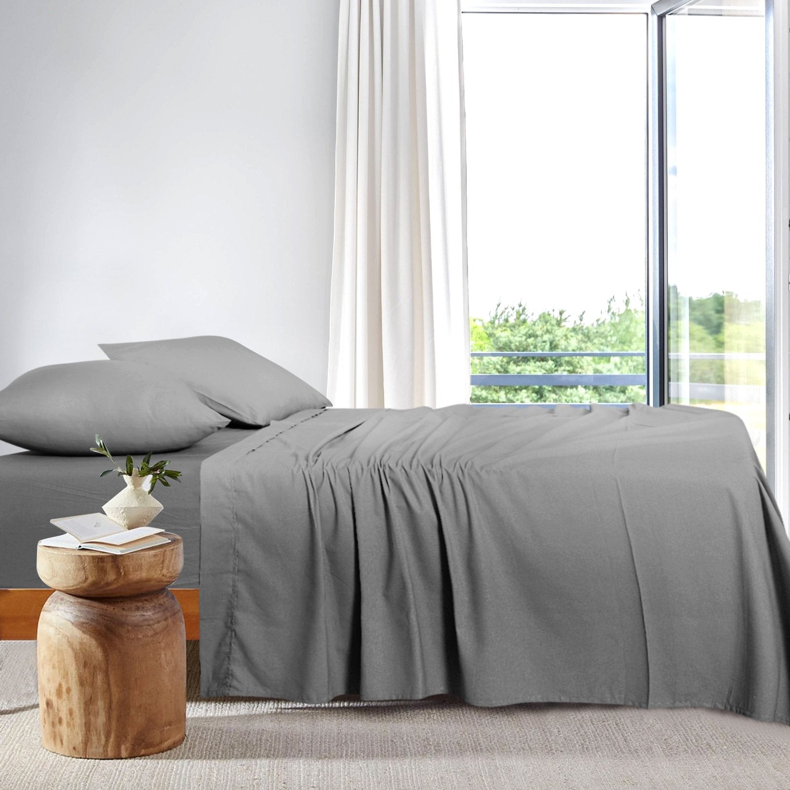 Pair of charcoal grey bamboo pillowcases resting on a made bed against a white wood-paneled wall