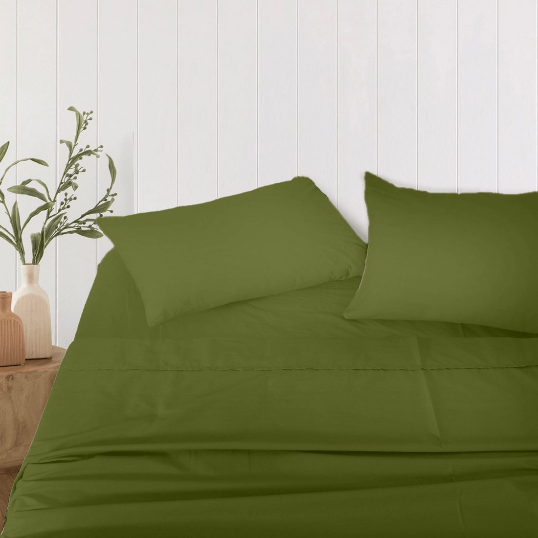 Pair of solid olive green bamboo pillowcases arranged neatly on a bed against a white wood-paneled wall