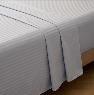 Fitted corner of a silver gray hotel stripe sheet smoothly tailored around a mattress