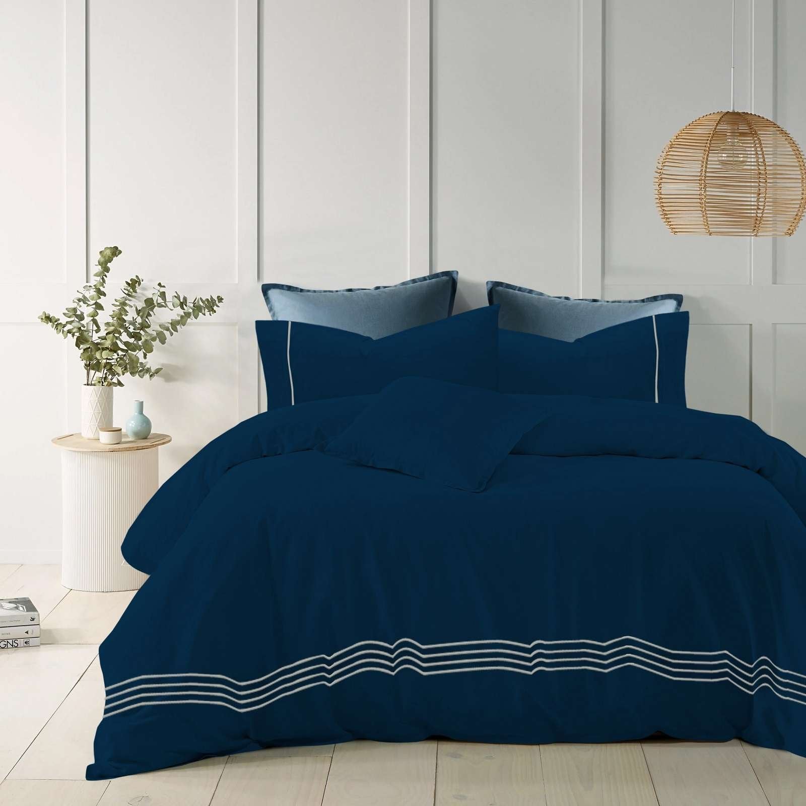 Navy blue cotton quilt cover with elegant embroidered stripes on a modern bed.