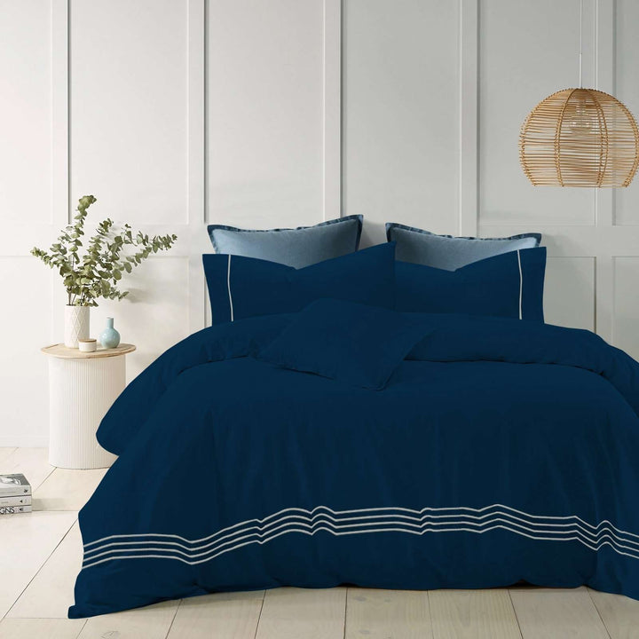 Navy blue cotton quilt cover with elegant embroidered stripes on a modern bed.