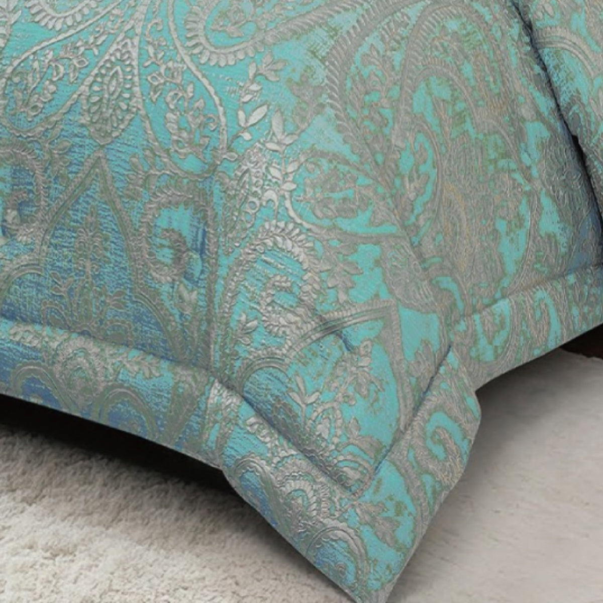 Close-up of teal jacquard fabric highlighting metallic paisley weave and tailored edge stitching