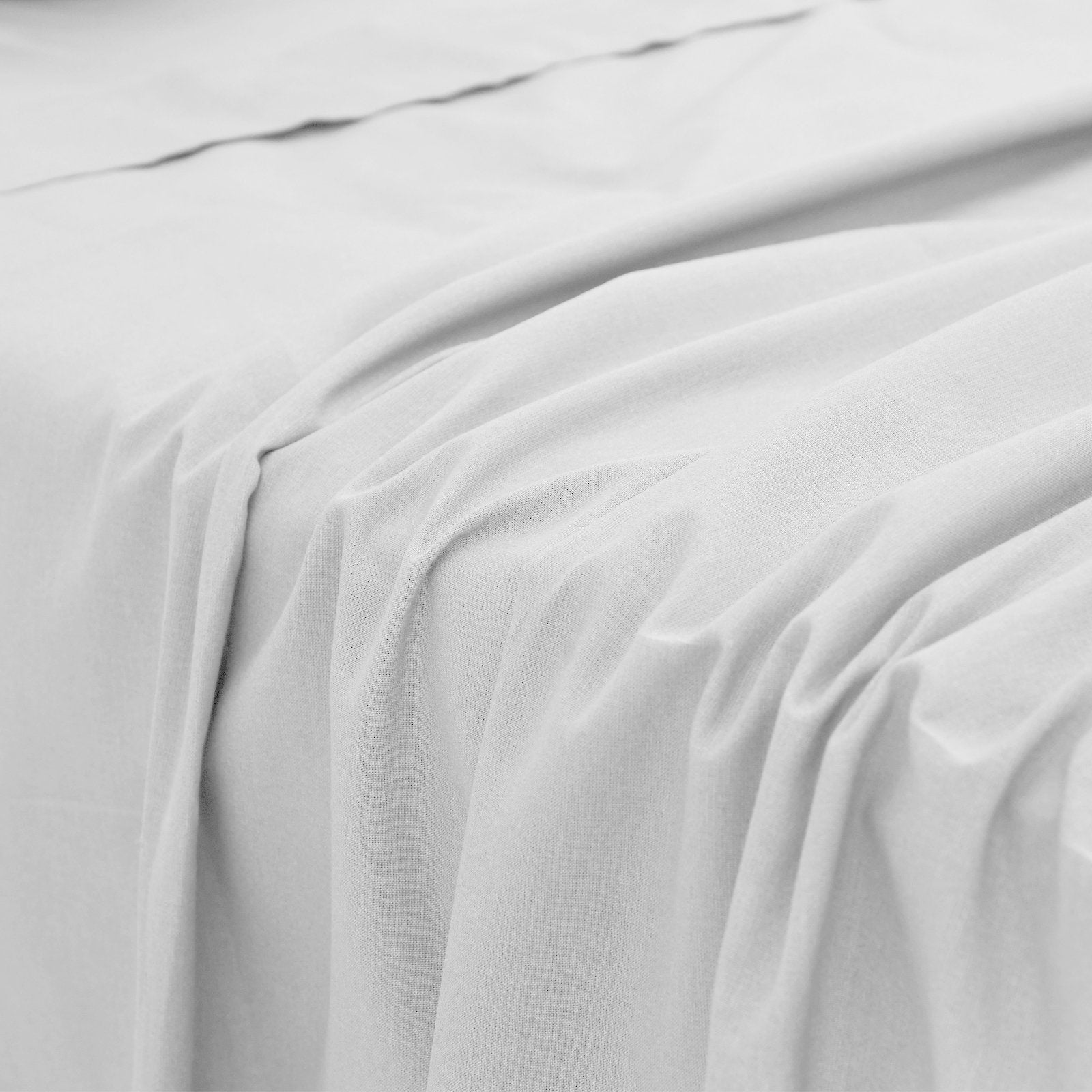 Close-up perspective of the smooth, lightweight fabric folds and soft texture of a white bamboo bed sheet.