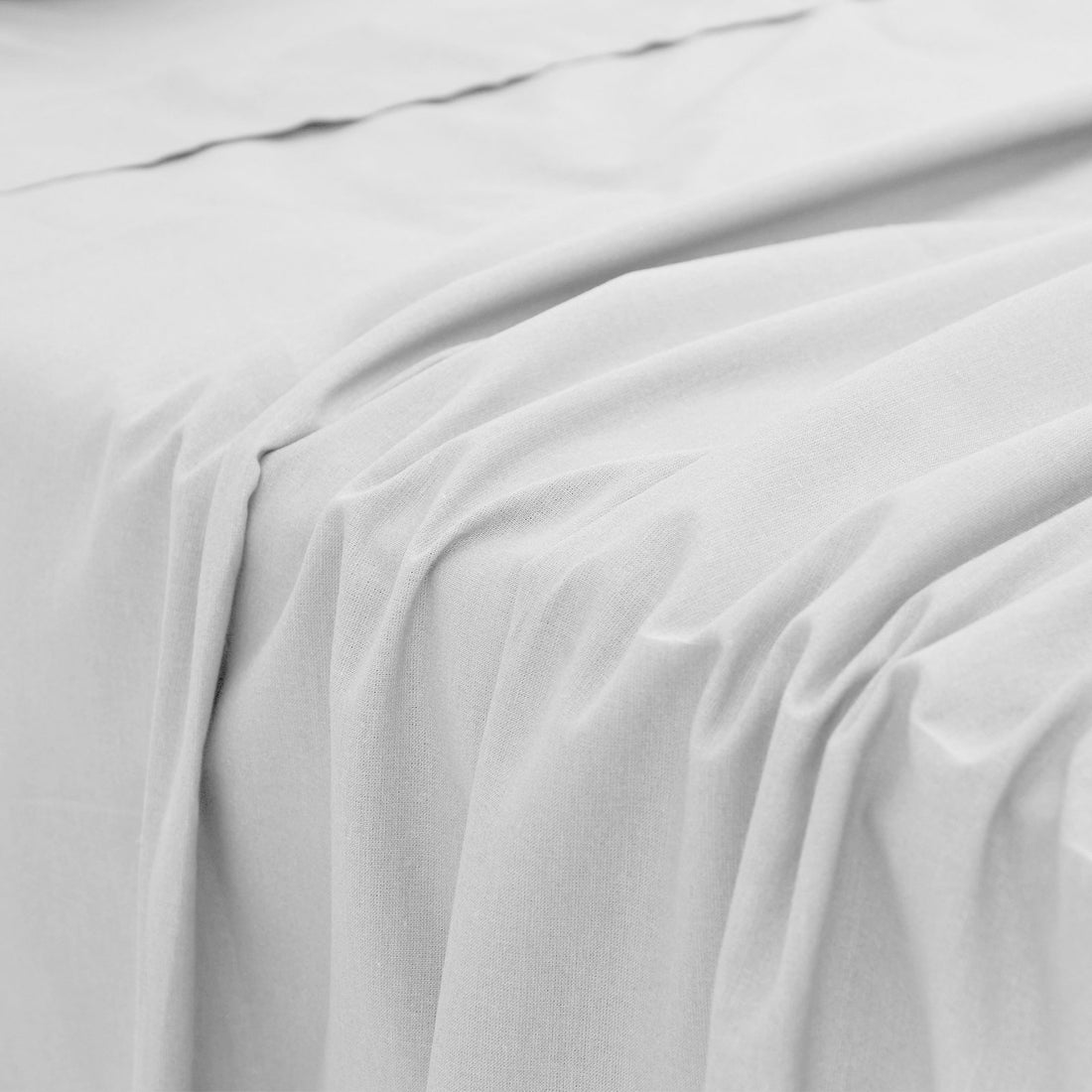 Close-up perspective of the smooth, lightweight fabric folds and soft texture of a white bamboo bed sheet.