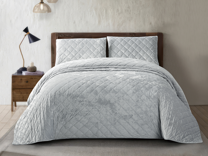 Luxury silver crushed velvet bedspread set styled on an elegant bedroom bed.