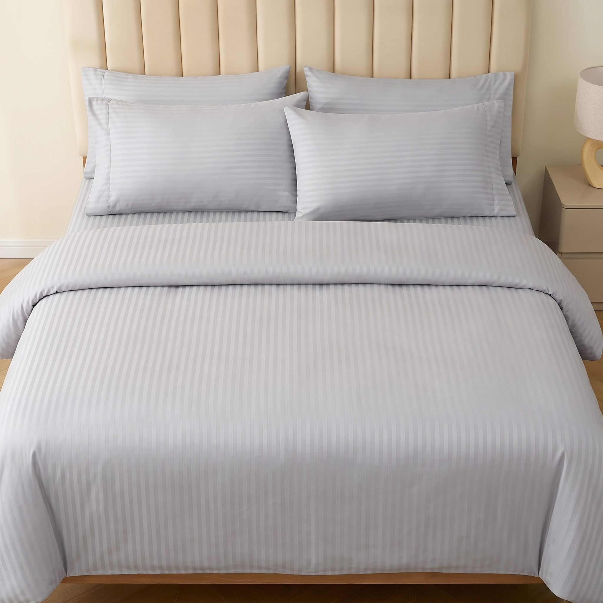 Full view of a luxury silver gray striped sheet set styled in a bright, modern bedroom.