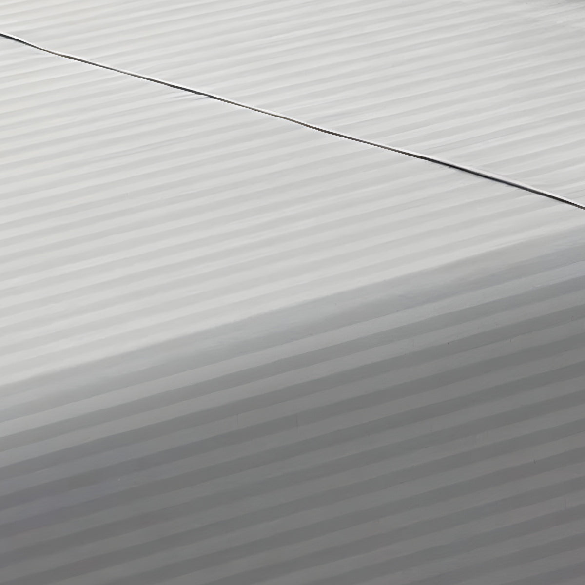 Close-up perspective of the smooth satin stripe weave of a silver gray cotton rich fitted sheet