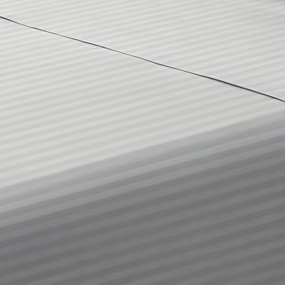 Close-up perspective of the smooth satin stripe weave of a silver gray cotton rich fitted sheet