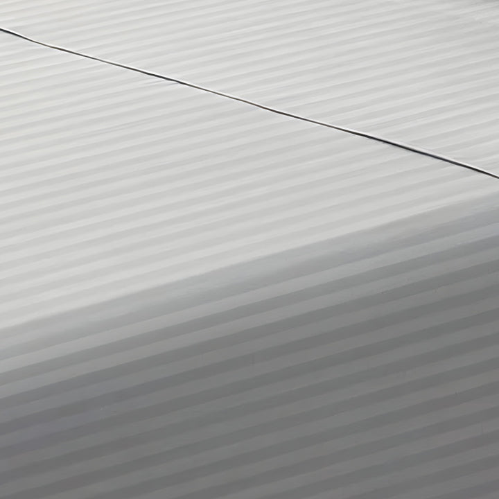Close-up perspective of the smooth satin stripe weave of a silver gray cotton rich fitted sheet
