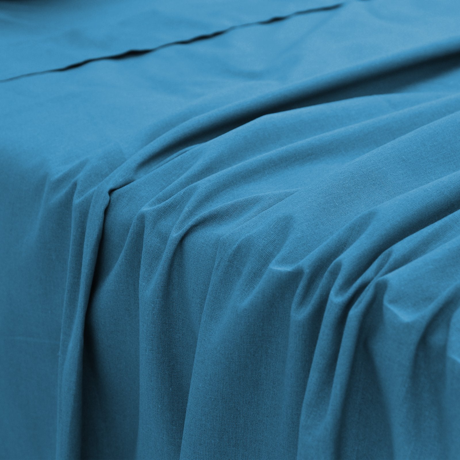 Close-up perspective of the smooth, fluid fabric folds of a blue bamboo bed sheet