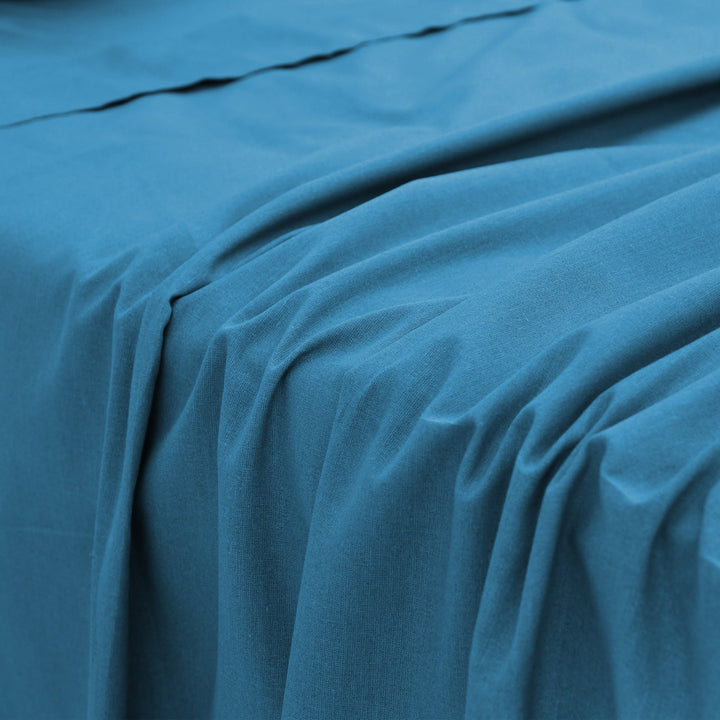 Close-up perspective of the smooth, fluid fabric folds of a blue bamboo bed sheet