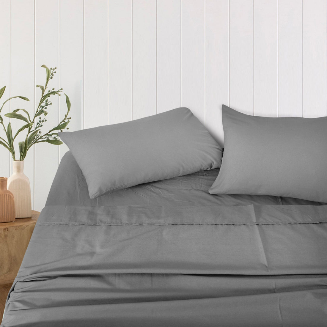 Neatly folded and rolled charcoal grey bamboo sheet set displayed against a plain background