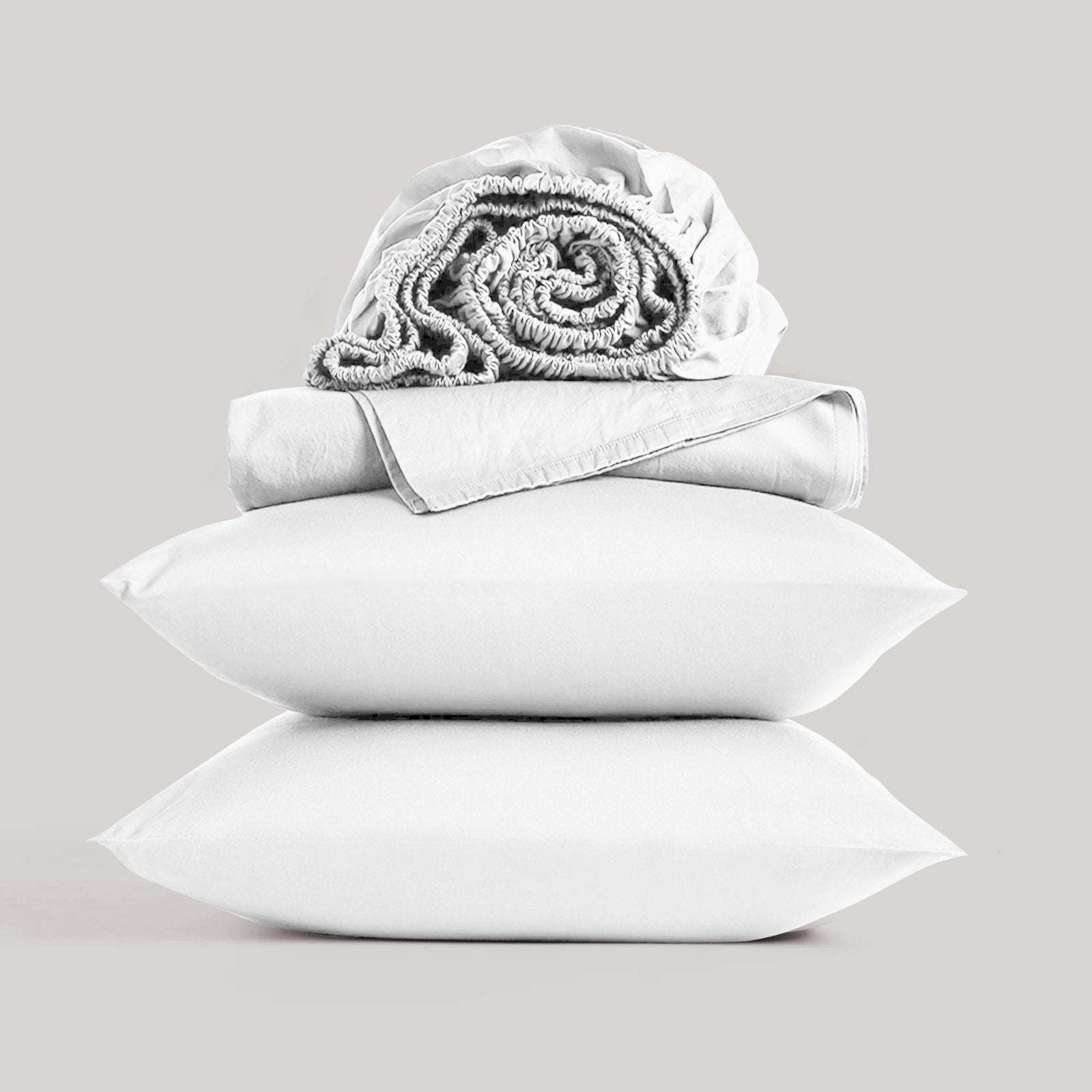 Neatly folded and rolled white bamboo sheet set displayed against a neutral studio background
