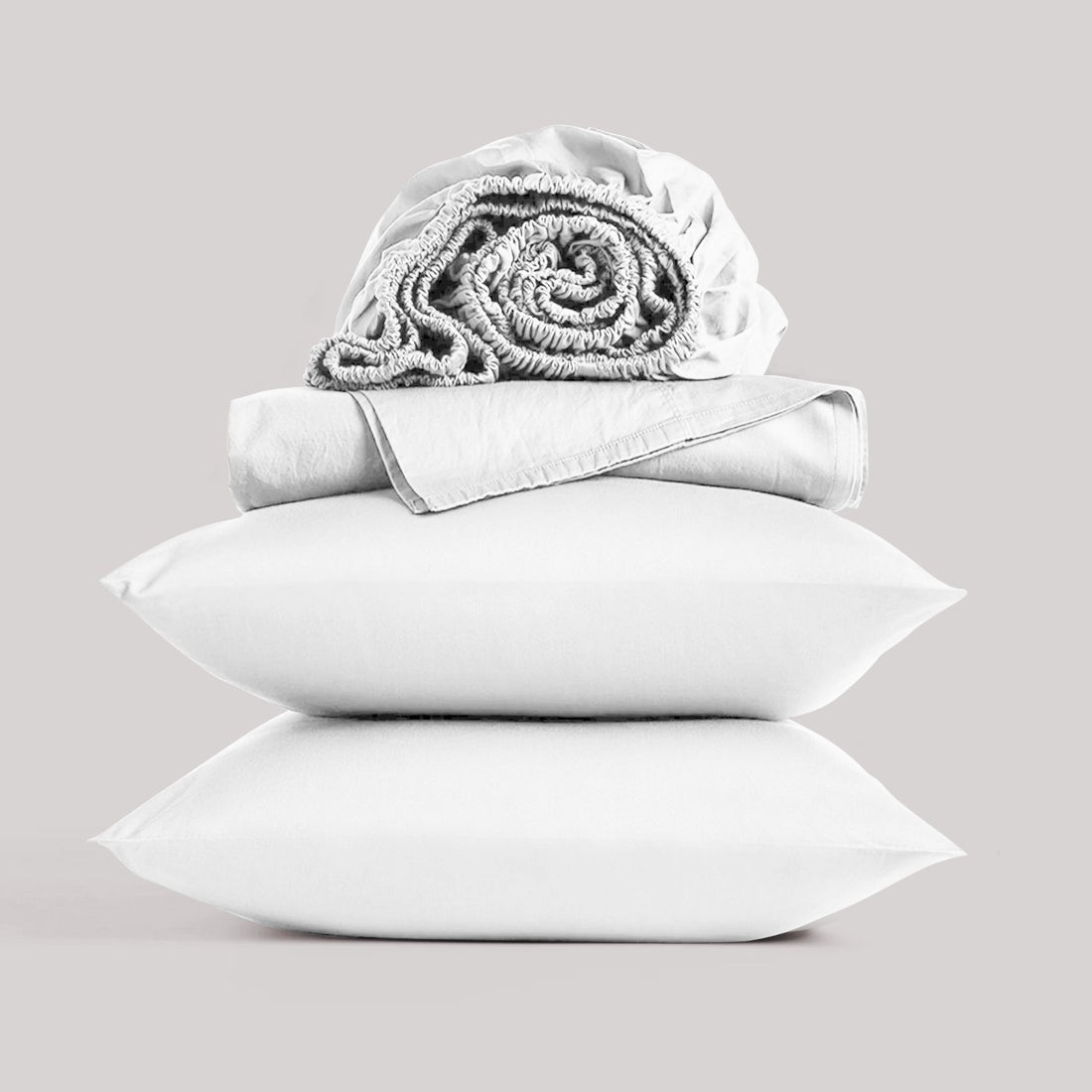 Neatly folded and rolled white bamboo sheet set displayed against a neutral studio background