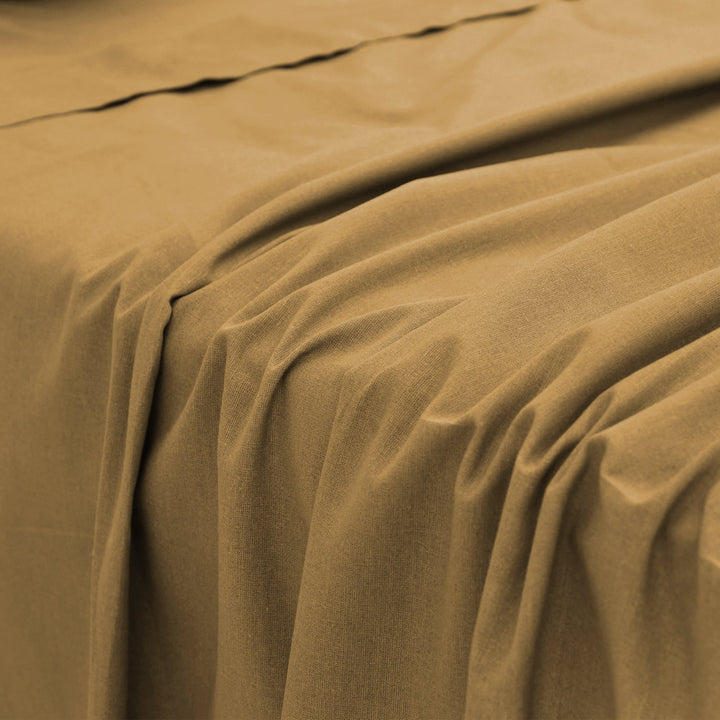Close-up perspective of the smooth fabric folds and silky drape of a taupe bamboo bed sheet
