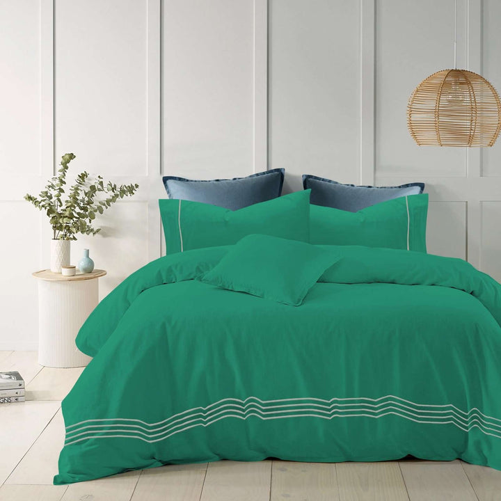 Teal cotton quilt cover with elegant embroidered stripes on a modern bed.