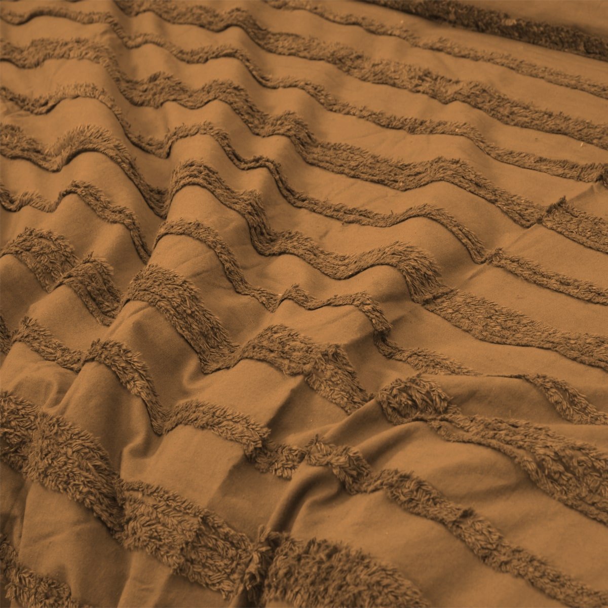 Close-up of camel quilt cover fabric with a wavy tufted design.