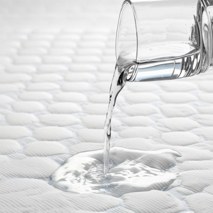 Water being poured from a glass onto an ultra cool waterproof mattress protector demonstrating liquid resistance