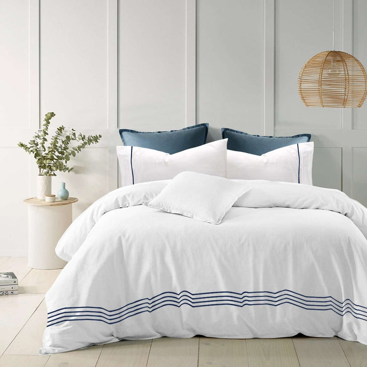White cotton quilt cover with blue embroidered stripes on a modern bed.