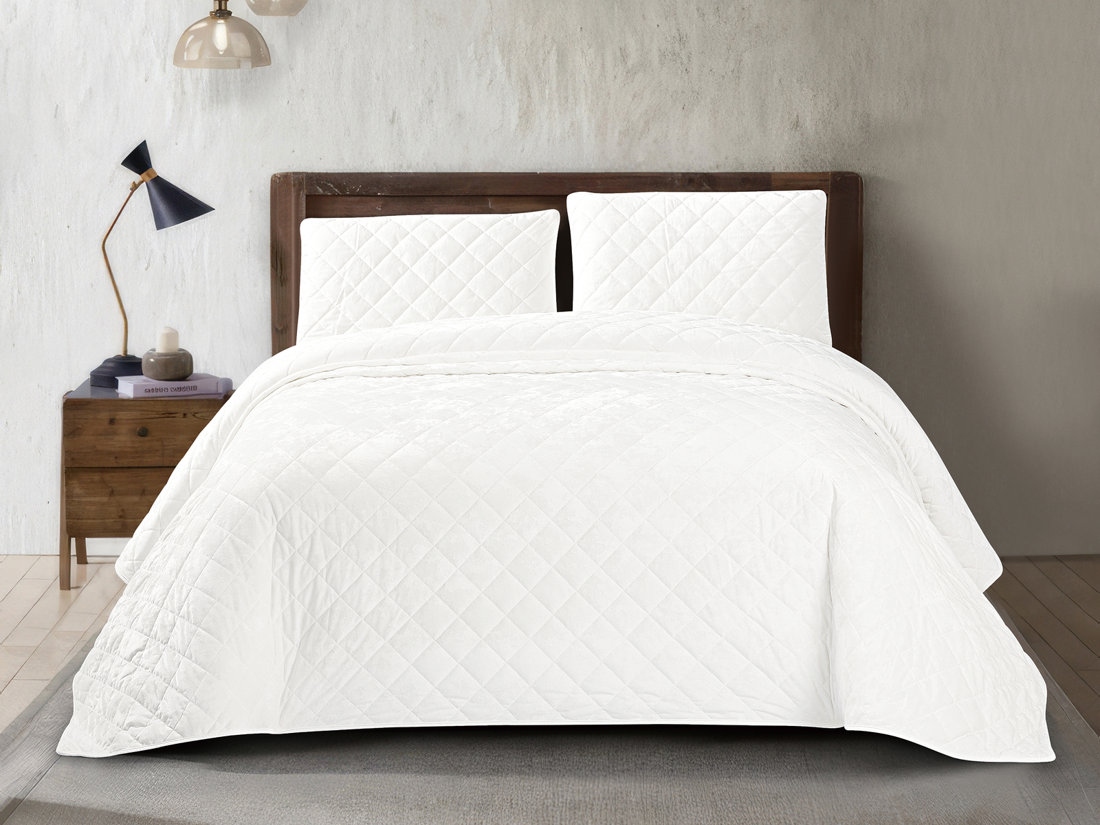 White crushed velvet bedspread set with diamond quilted detailing and matching pillows on a modern bed.