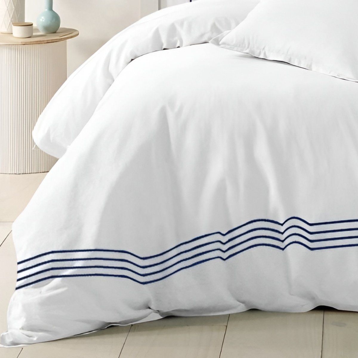White bedding featuring an elegant blue striped border design.