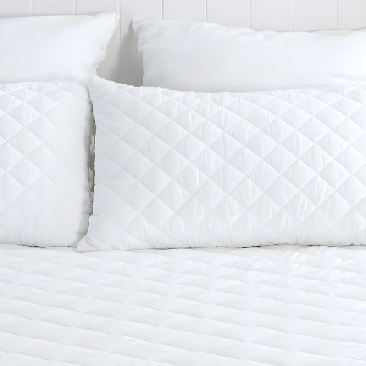 Full view of a white diamond quilted mattress protector styled neatly in a bright, modern bedroom